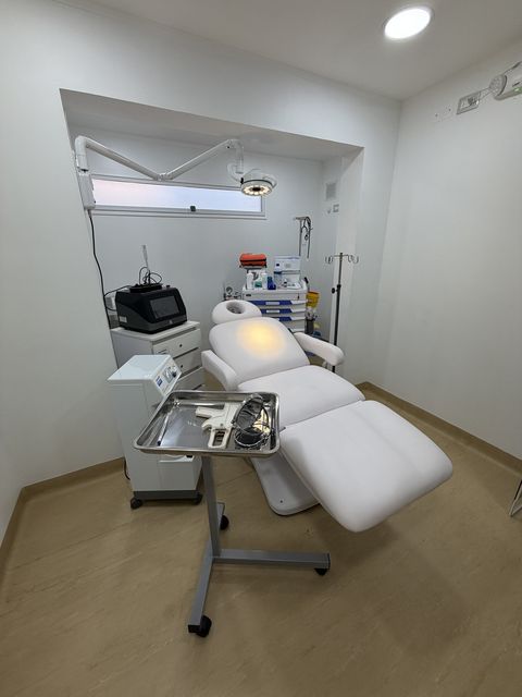Box de procedimientos de medicina estética, con camilla clínica, lámpara y carro de instrumental
